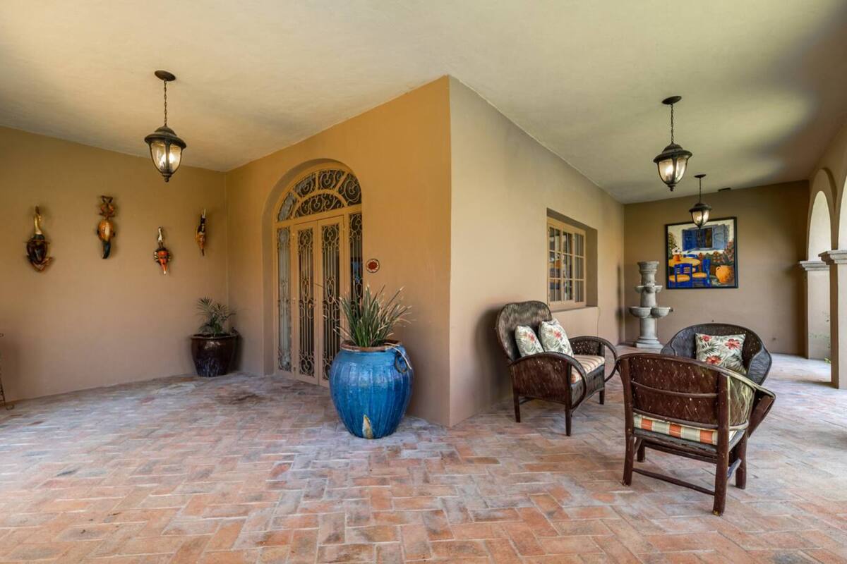 A spacious interior with a brick floor, a large blue vase, wicker furniture, and decorative wall art.