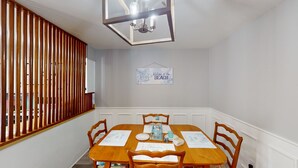 A dining area with a wooden table, four chairs, and a 'Welcome to the Beach' sign on the wall. - Turtle's Nest Duplex 3 bedrooms, 2 bathrooms (Jekyll Island)