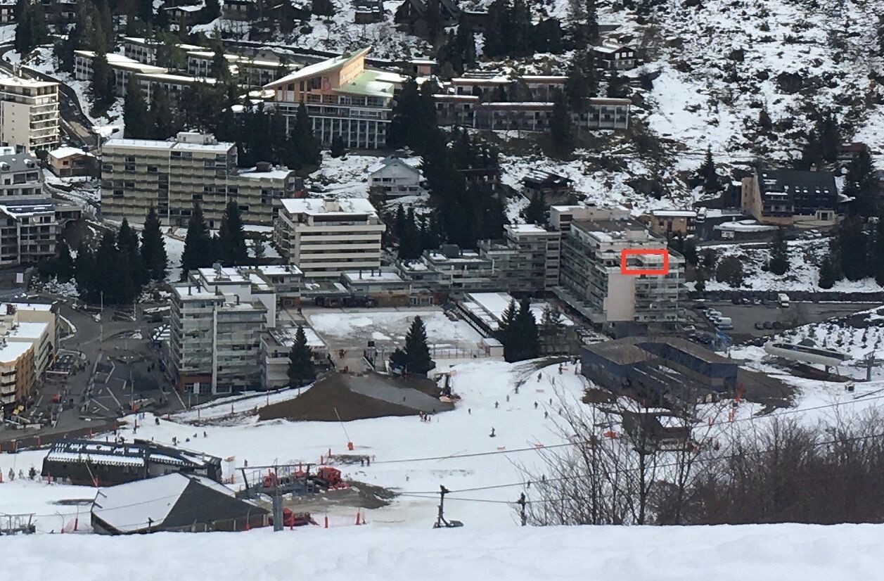 A snow-covered town with buildings, a ski lift, and a ski slope.