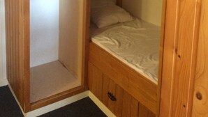 Une chambre avec un lit superposé, une armoire en bois et un portant à vêtements.