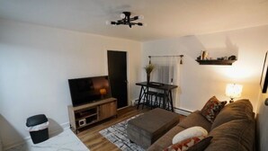 A living room with a sofa, TV, and a small table with chairs. - Pet friendly fully furnished and private 1 Bedroom Flat (Fond du Lac)