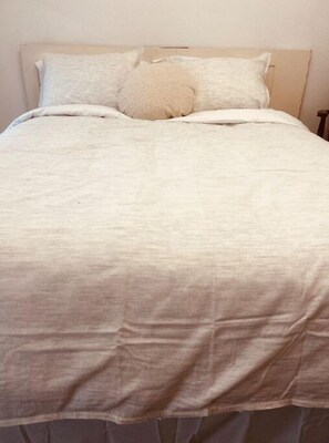 Comfortable bed with a bedspread and two pillows, accompanied by a nightstand.