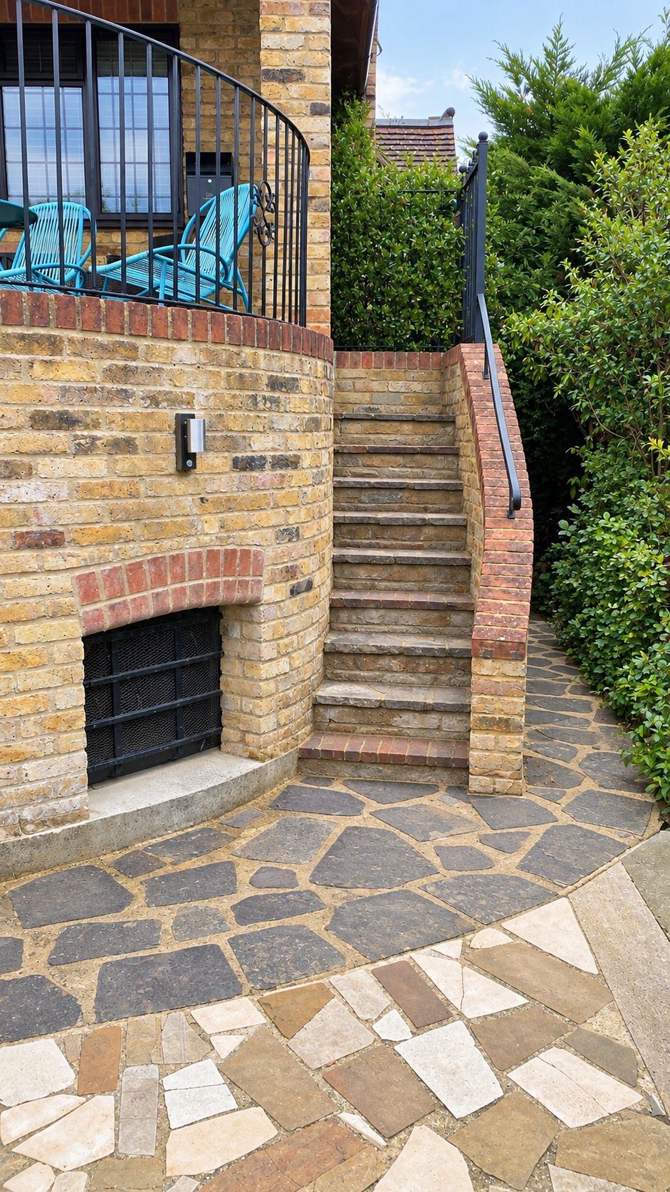A stone staircase leading to a brick wall with a metal railing, a door, and a small window.