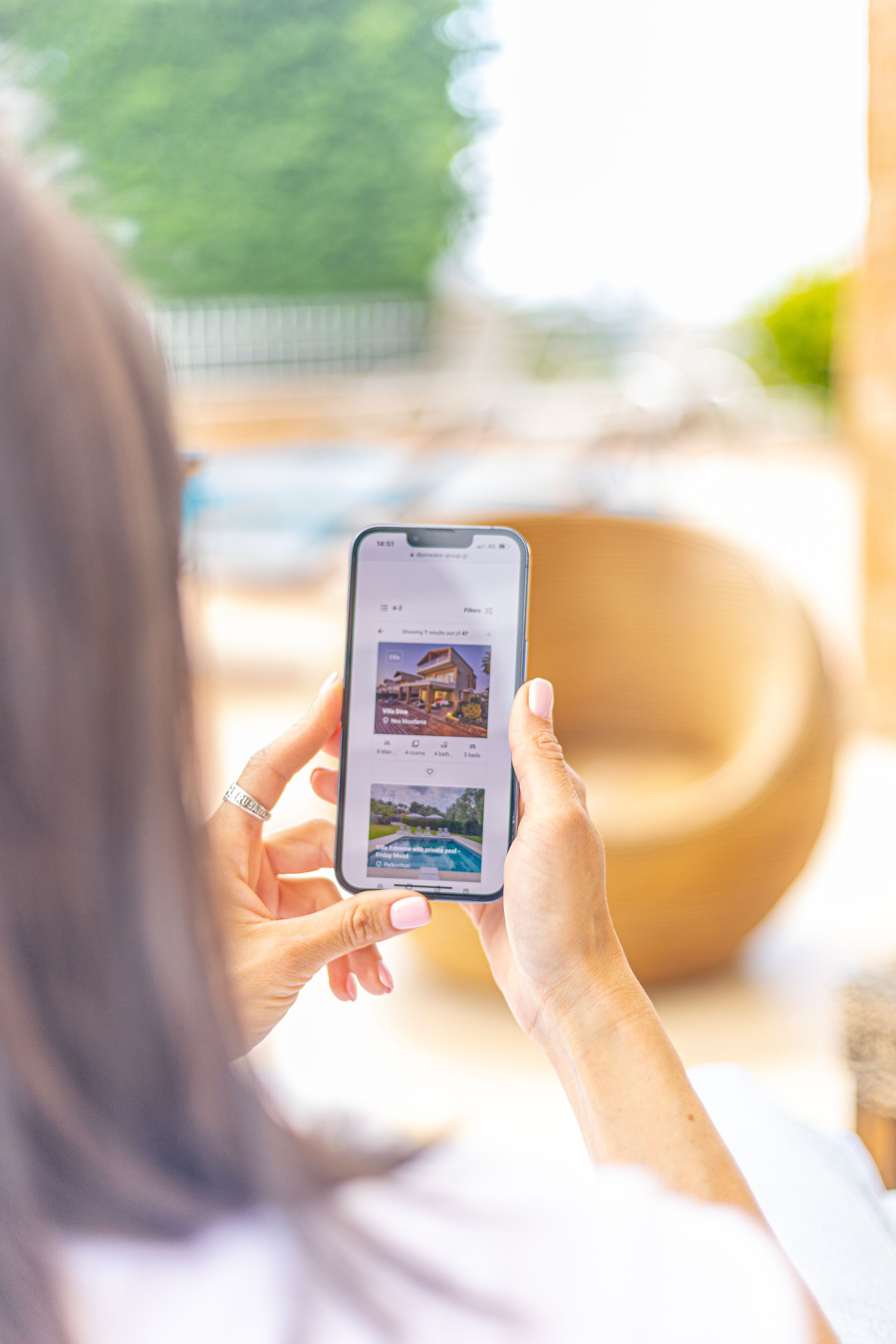A person holding a smartphone displaying a property listing.