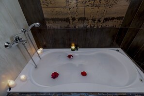 A bathtub with rose petals and candles, set against dark wooden walls. - Villa Nefeli (Nea Propontida)
