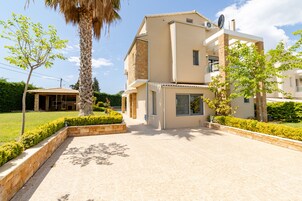 Una casa moderna de dos pisos con techo plano, ventanas grandes y una antena parabólica.