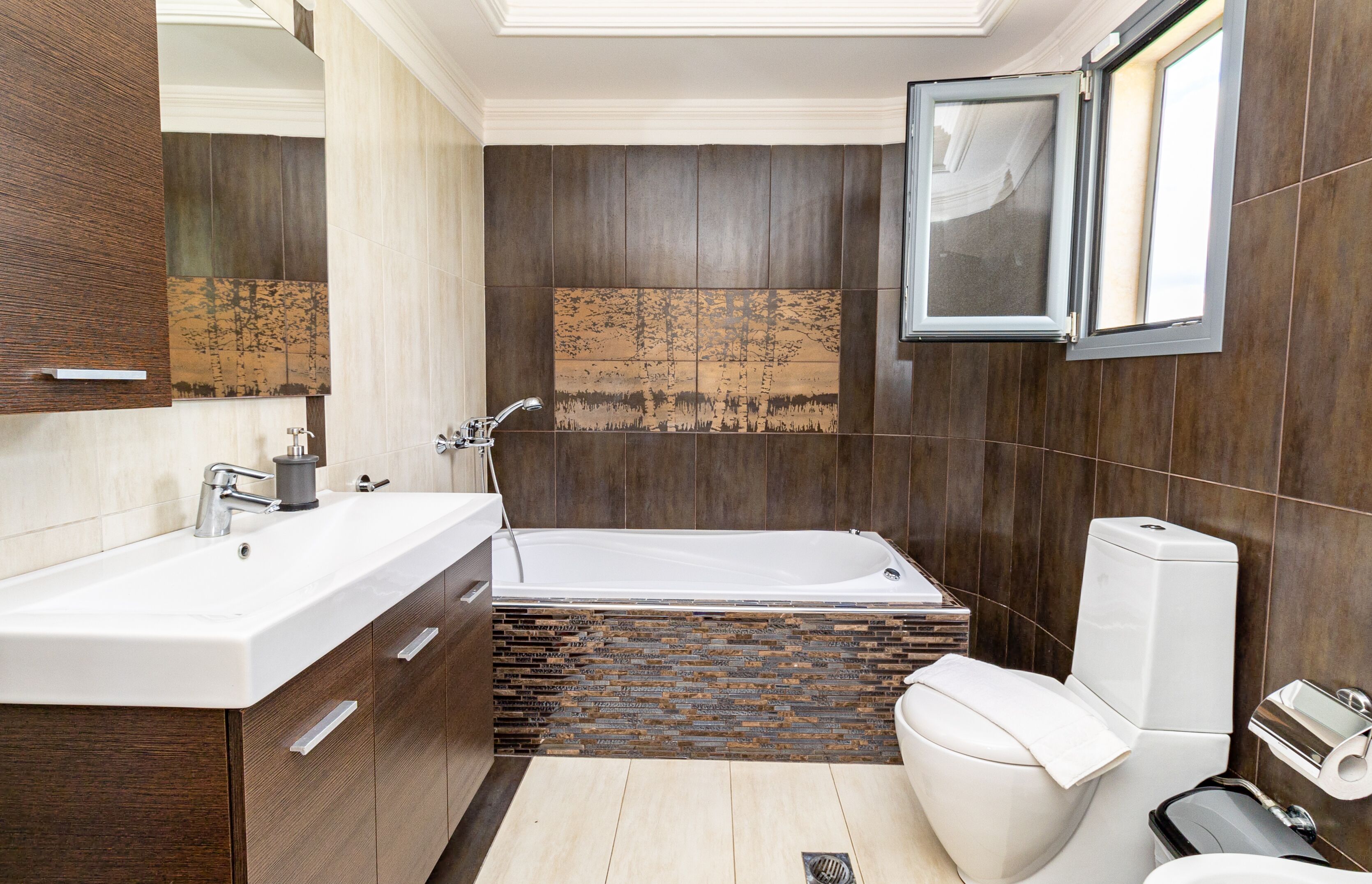 A modern bathroom with a large bathtub, a white sink, and dark wood paneling.