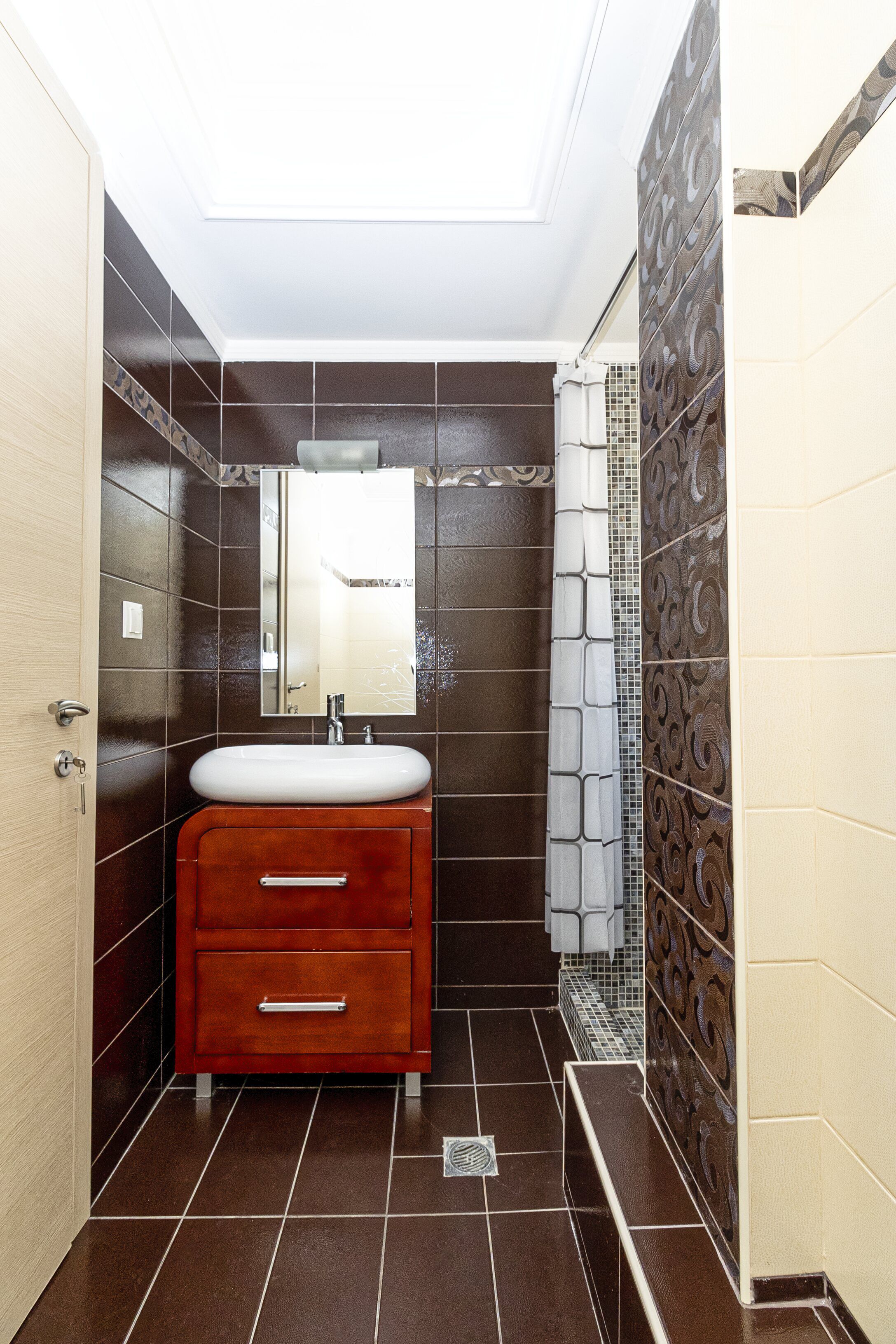 A bathroom with a vanity, mirror, and tiled walls.