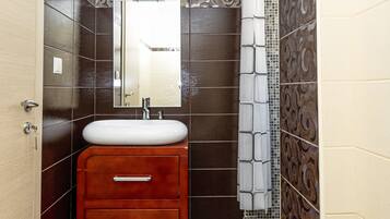 A bathroom with a vanity, mirror, and tiled walls.