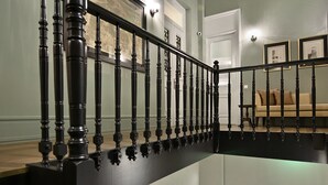 Eine mehrstufige Treppe mit schwarzen Geländern und einem hölzernen Handlauf.