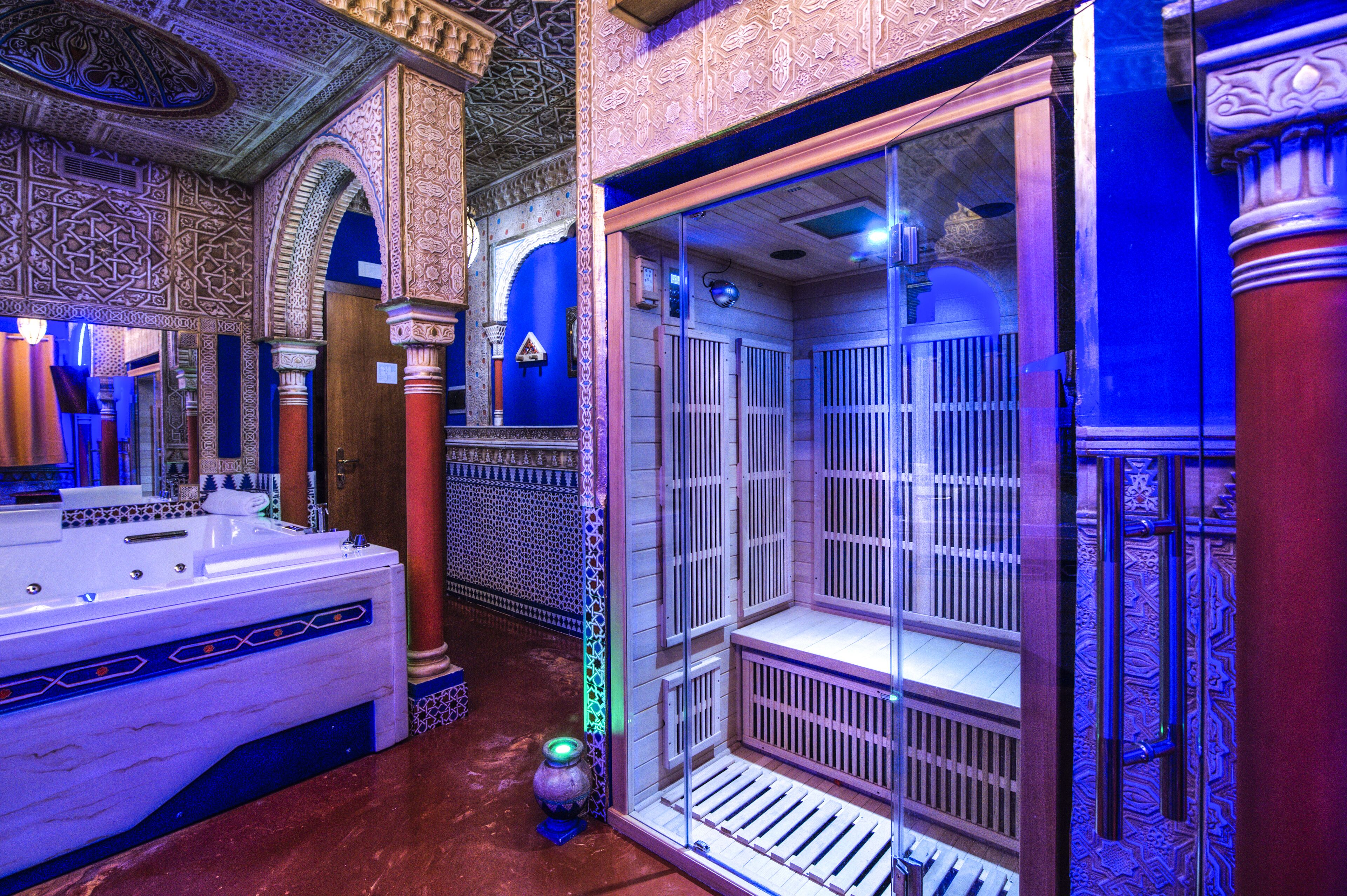 Un baño lujoso con una bañera de mármol, detalles de azulejos ornamentales y una zona de ducha con mampara de vidrio.
