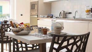 A breakfast table with a bowl of bread and condiments, a coffee cup, a water bottle, and a "BREAKFAST" mug. - MarGab B&B Green Room (Napoli)