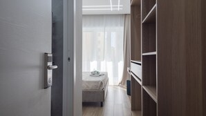 A modern bedroom with a bed, a wardrobe, and a door with a handle. - MarGab B&B Green Room (Napoli)