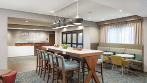 Eine Hotelhalle mit Rezeption, Bar und Sitzgelegenheiten, darunter eine Couch und Stühle.