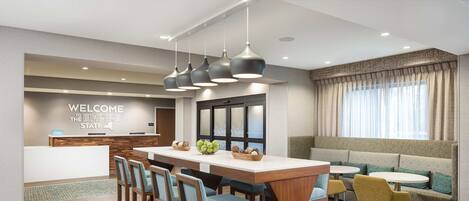 A hotel lobby with a reception desk, a bar area, and seating arrangements including a sofa and chairs.