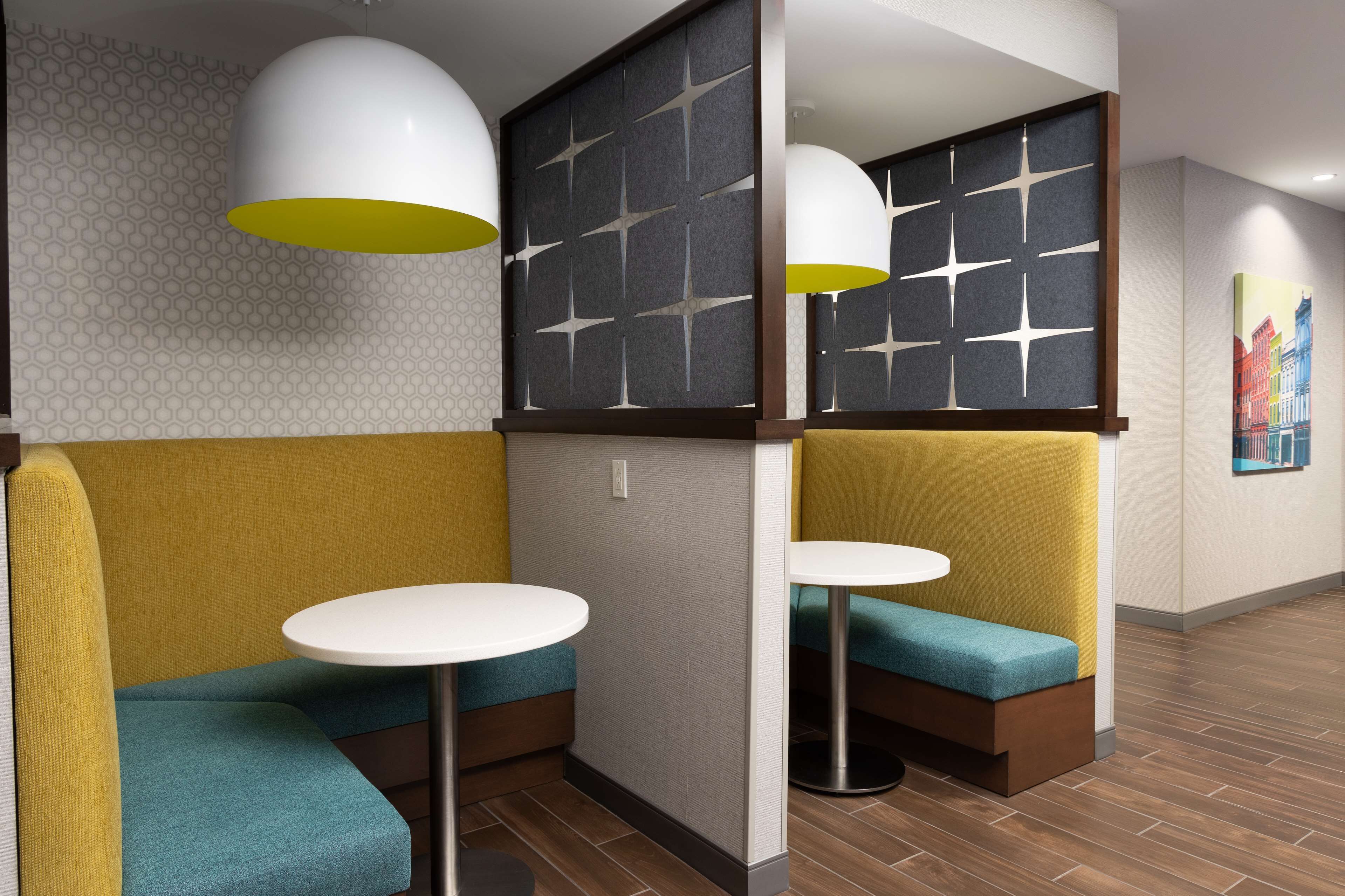 A modern interior with seating areas, round tables, and decorative wall panels.