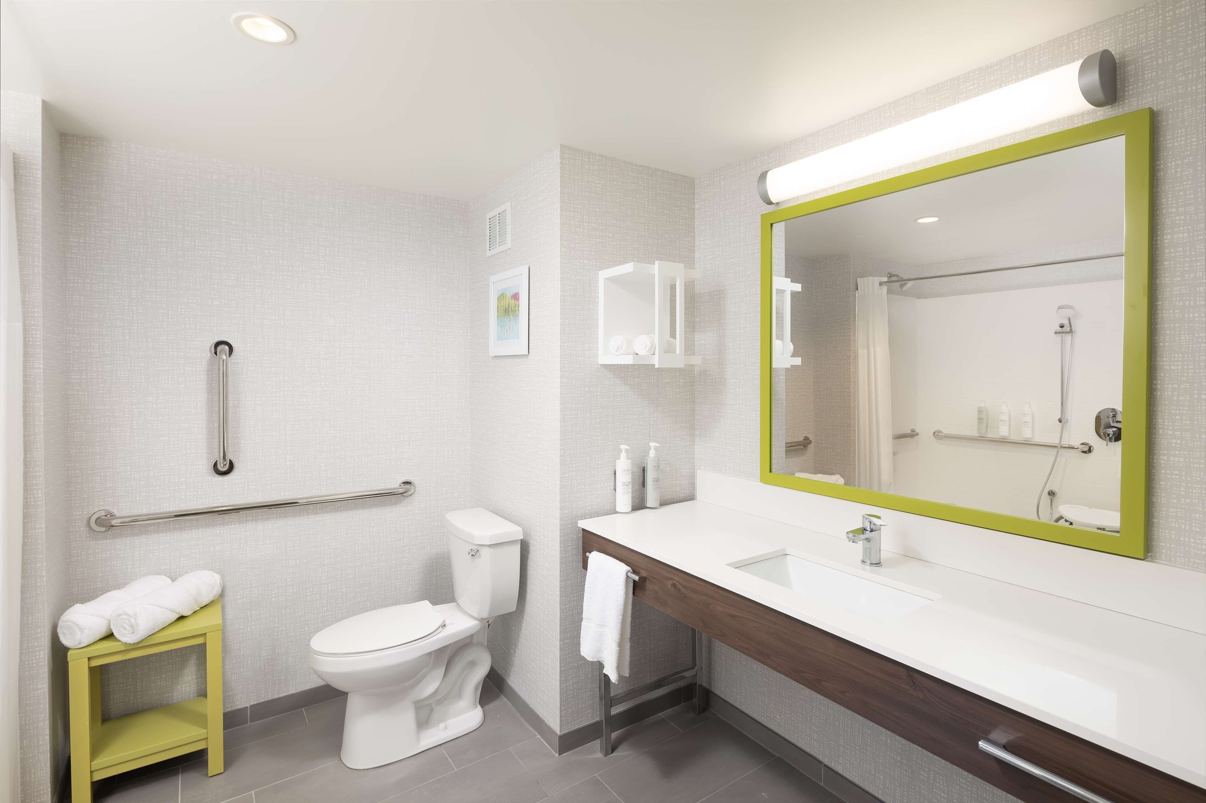 Un baño moderno con un inodoro blanco, un tocador de madera con un espejo y una barandilla.