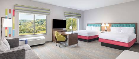 A hotel room with a large window, a desk with a chair, two beds, and a couch.