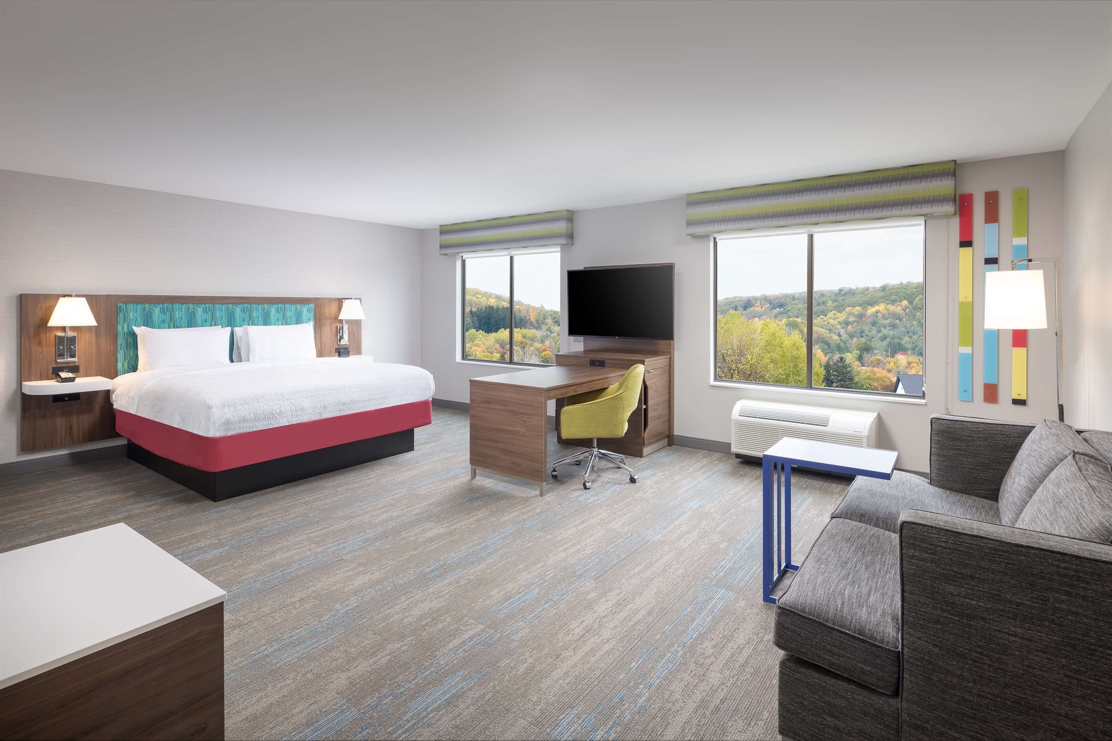 Una habitación de hotel con cama, escritorio y sofá.