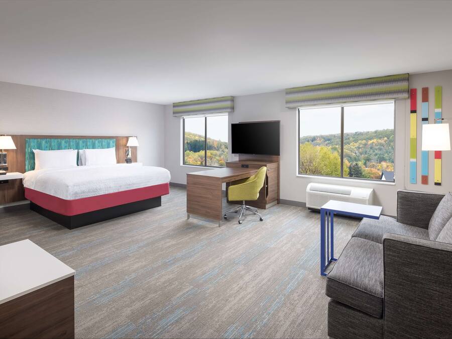 Una habitación de hotel con cama, escritorio y sofá.