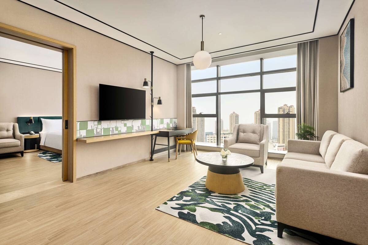 A modern living room with a flat-screen TV, a round coffee table, and a sofa.