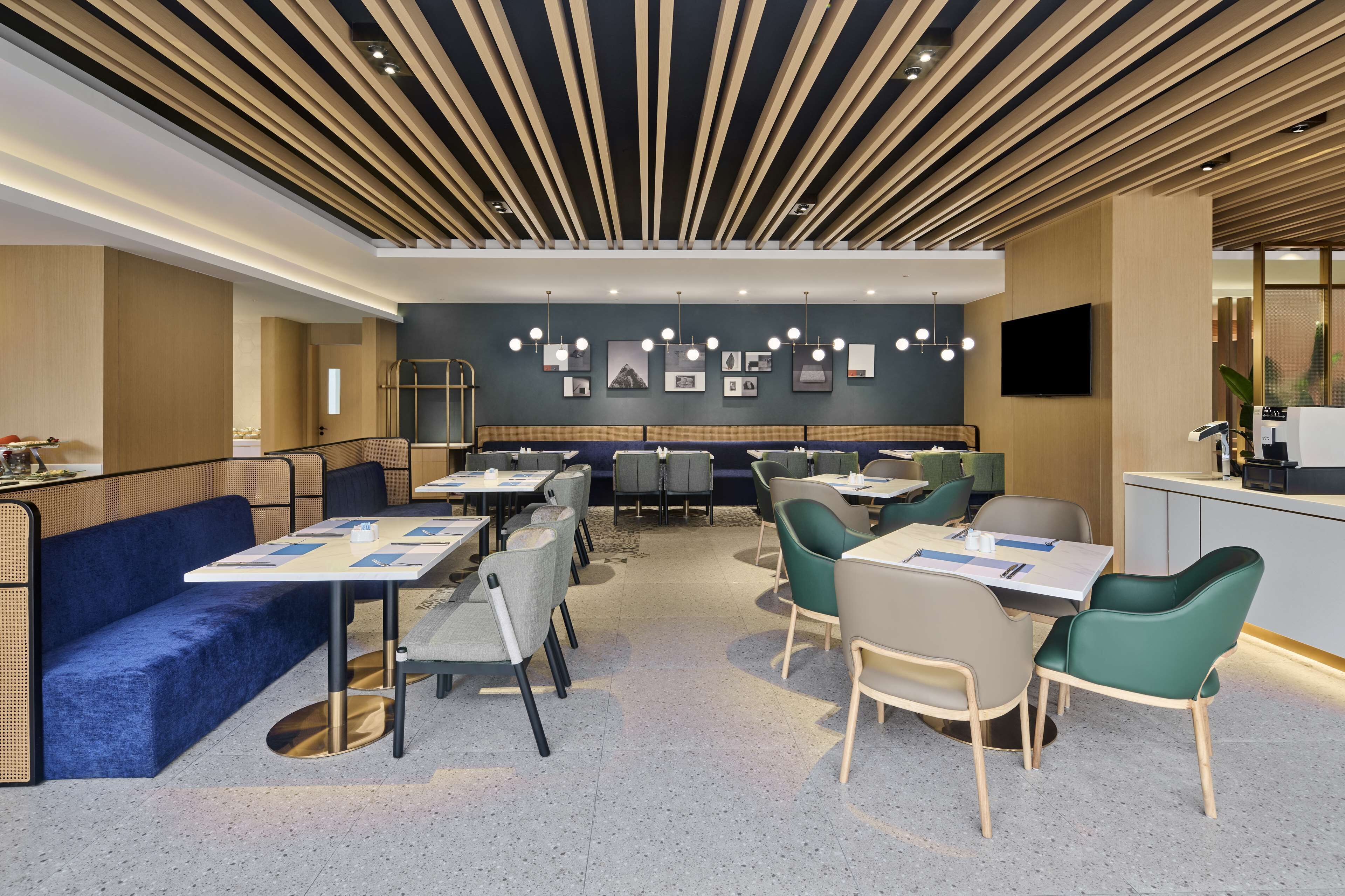 A modern restaurant with a central seating area, a bar, and a kitchen visible in the background.
