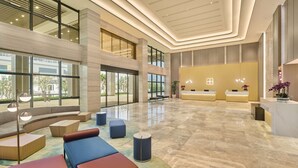 Un vestíbulo amplio con mostrador de recepción, zonas de estar y grandes ventanales con vistas al exterior.