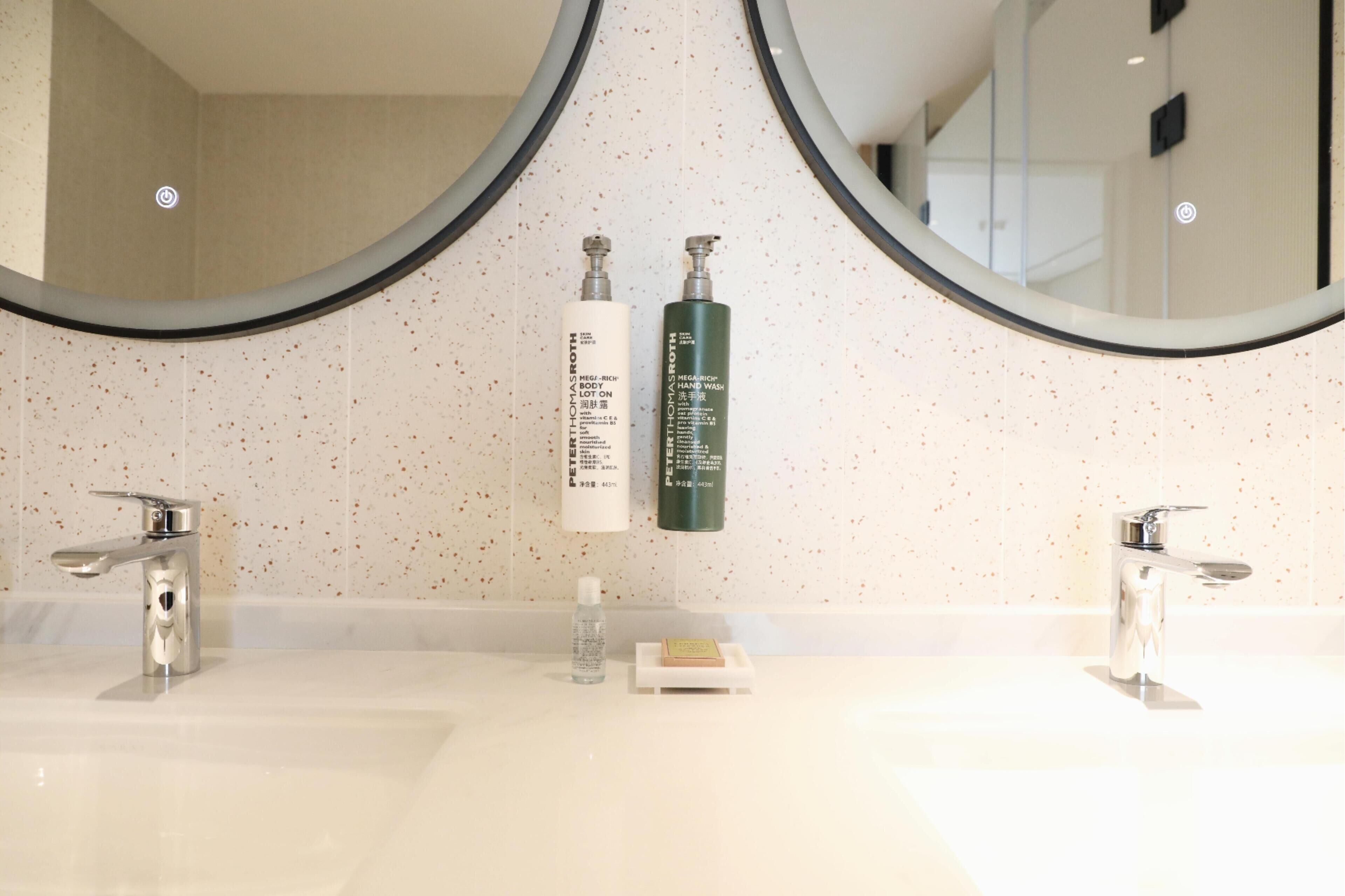 A bathroom with two sinks, a large mirror, and toiletries on the counter.