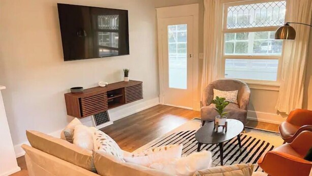 A living room with a sofa, a coffee table, and a TV mounted on the wall. - Modern Comfort in a Bright Nampa Retreat (Nampa)