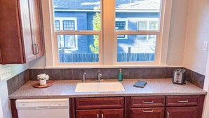 A compact kitchen with a window, a dishwasher, and wooden cabinets. - Modern Comfort in a Bright Nampa Retreat (Nampa)