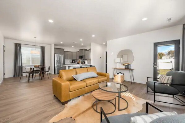 A modern living room with a sofa, a coffee table, and a dining area with chairs. - New Modern Cozy Home in Meridian (Meridian)
