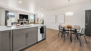 A modern kitchen with a central island, dining table with chairs, and pendant lighting. - New Modern Cozy Home in Meridian (Meridian)