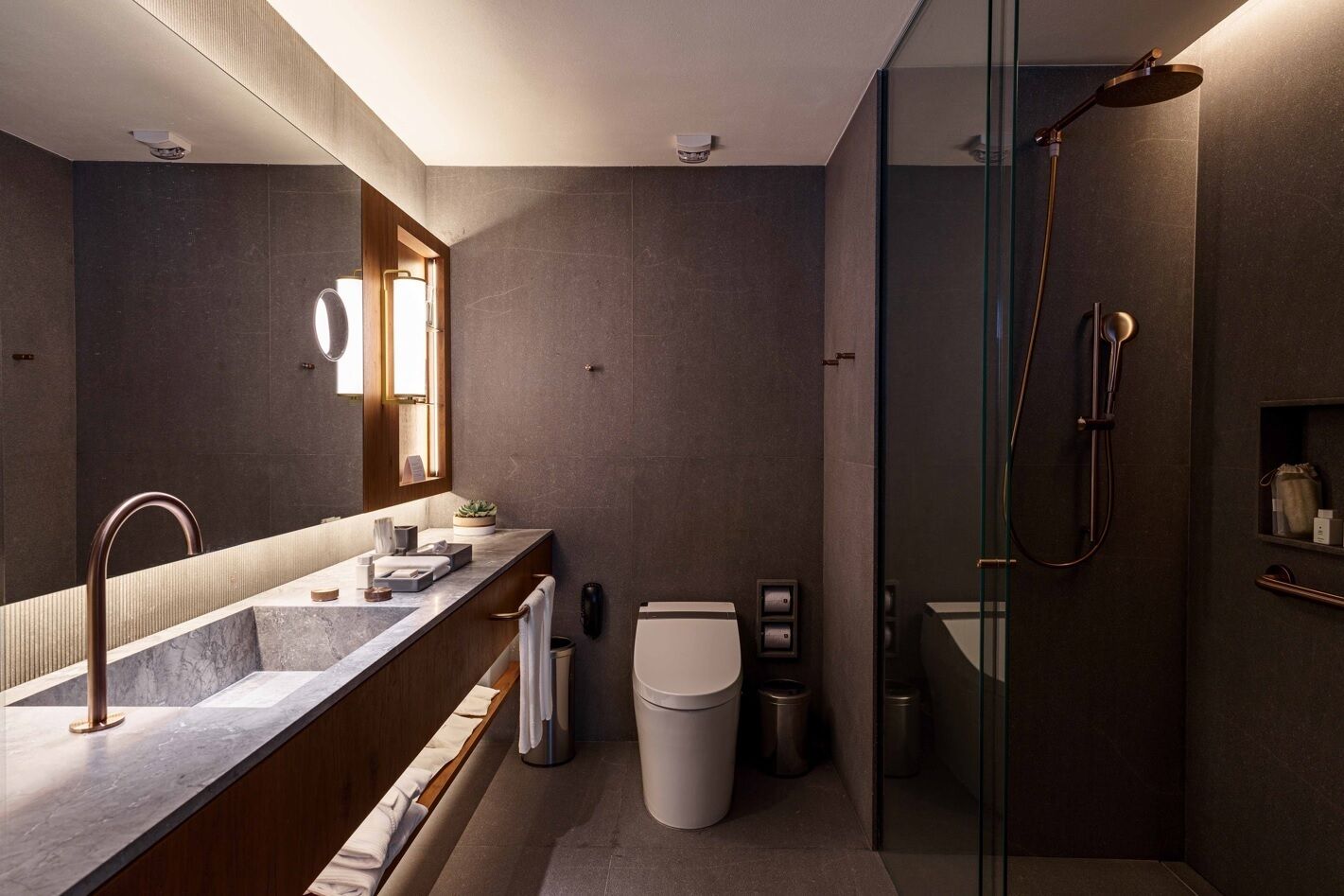 Ein modernes Badezimmer mit einer gläsernen Duschkabine, einem großen Spiegel und einem мраморный Waschtisch.