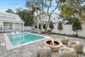 A swimming pool with lounge chairs, a fire pit, and a white building with a balcony. - 1 Minute to Beach, with Private Heated Pool, Carriage House, and Fire Pit (Santa Rosa Beach)