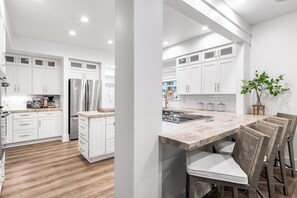 Une cuisine moderne avec des meubles blancs, un réfrigérateur en acier inoxydable et un plan de travail en marbre.
