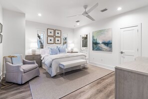 A bedroom with a bed, bedside tables, a chair, a bench, a ceiling fan, and artwork on the walls. - 1 Minute to Beach, with Private Heated Pool, Carriage House, and Fire Pit (Santa Rosa Beach)