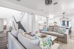 Un salon moderne avec un escalier, un coin repas et une cuisine.