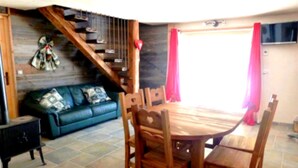 A dining area with a wooden table and chairs, a blue sofa, and a staircase leading to an upper level. - CHALET LES CLARINES between lake and mountains (Bluffy)