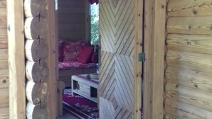 A wooden cabin with a chevron-patterned door, a bed with red bedding, and a small table. - CHALET LES CLARINES between lake and mountains (Bluffy)