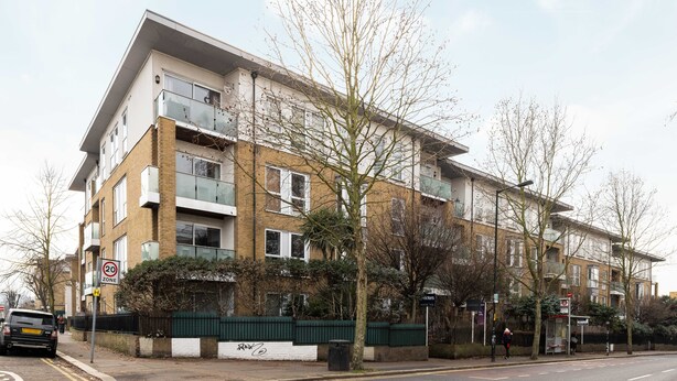 A multi-story residential building with a 20 mph speed limit sign, a bus stop, and a green fence. - The East Dulwich Villas (London)