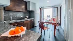 A modern kitchen with dark wood cabinets, a marble countertop, and a dining area with a table and chairs. - Apartment overlooking the sea of Cefalù (Cefalù)