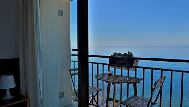 A balcony with a table and chairs, a small plant, and a view of the sea. - Apartment overlooking the sea of Cefalù (Cefalù)