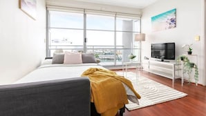 A modern bedroom with a large bed, a TV, and a balcony with a view of the city. - A Comfy & Spacious 2BR Apt Harbour View (Sydney)