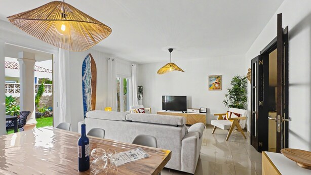 Un salon moderne comprenant un coin repas, un canapé, un téléviseur et une grande fenêtre.