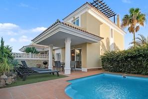 Une maison avec une piscine, un patio couvert et une pergola.
