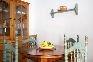 A dining table with chairs, a bowl of lemons, and a wooden cabinet with glass doors.
