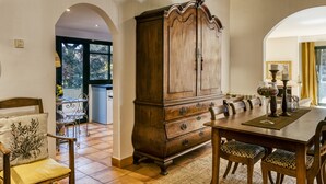 Un coin repas comprenant un buffet en bois, une table, des chaises et une vue dégagée sur l’espace adjacent, accessible par une arche.