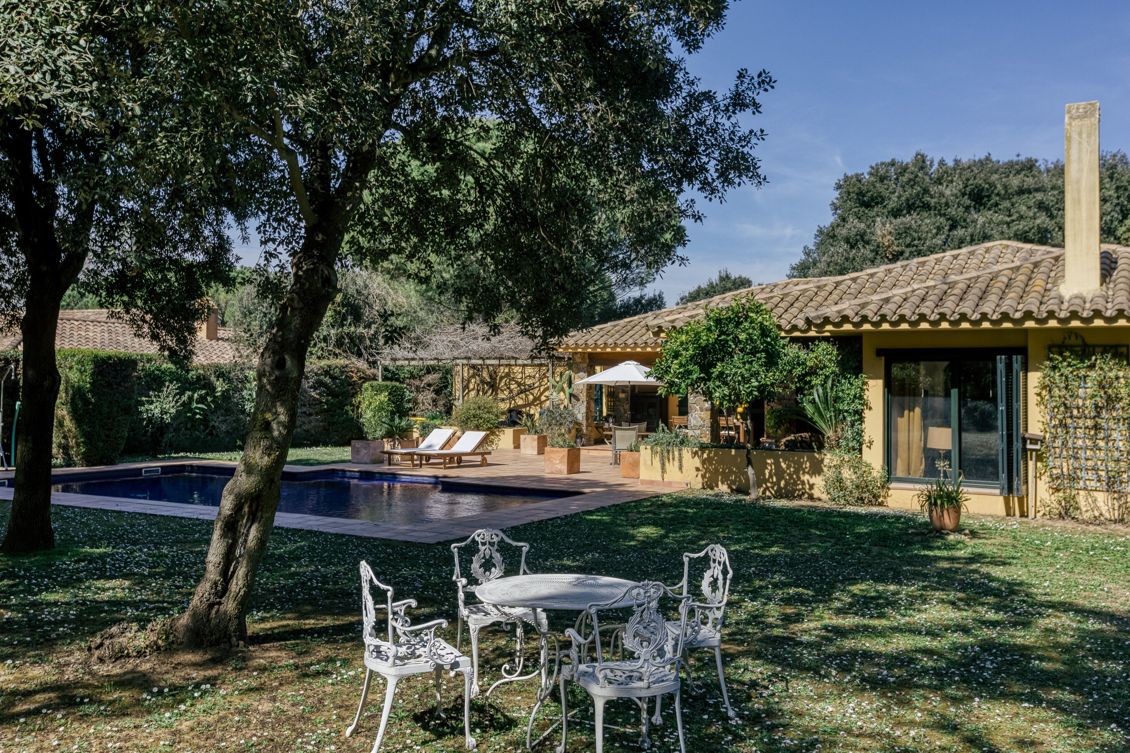 A villa with a swimming pool, outdoor seating, and a garden.