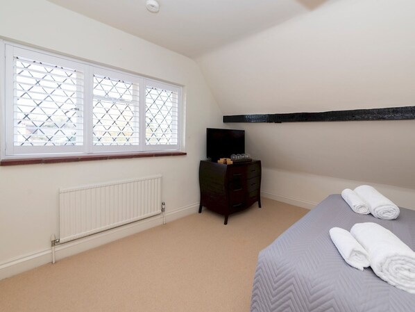 A bedroom with a bed, a dresser, a radiator, and a window with blinds.