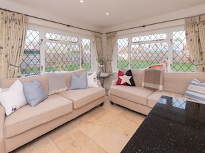 Relax in this serene living room with two sofas, a side table, and large windows.